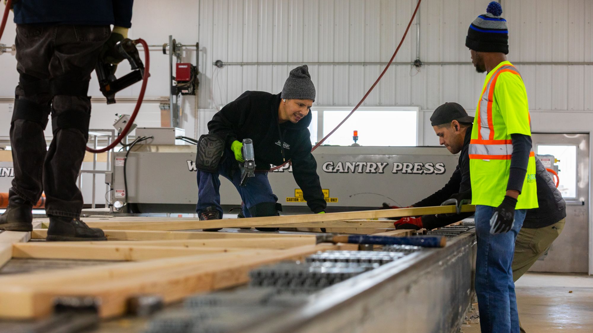 Crew members positioning lumber at the gantry press table.